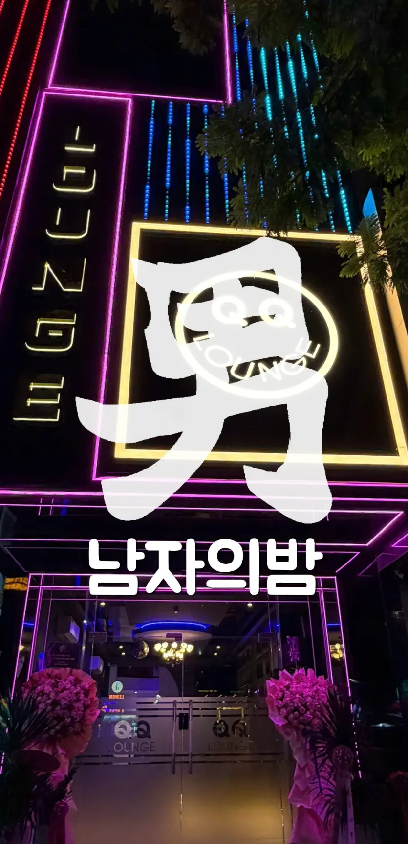 다낭 QQ LOUNGE 입구 위 웃는 얼굴 모양 QQ LOUNGE 네온 간판과 오픈 화환