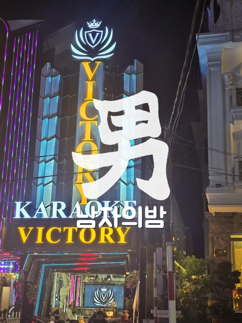 달랏 빅토리 가라오케 밤 전면의 세로 VICTORY 간판과 왕관 방패 로고