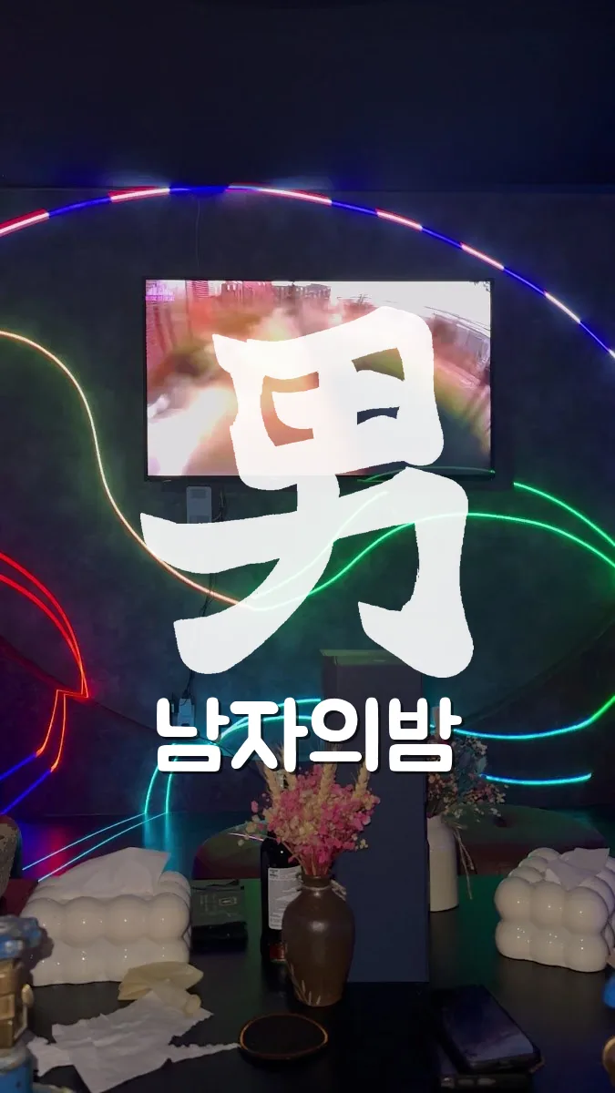 나트랑 버니바 네온 라인 조명이 둘러진 벽과 화면, 테이블 위 드라이플라워 화병